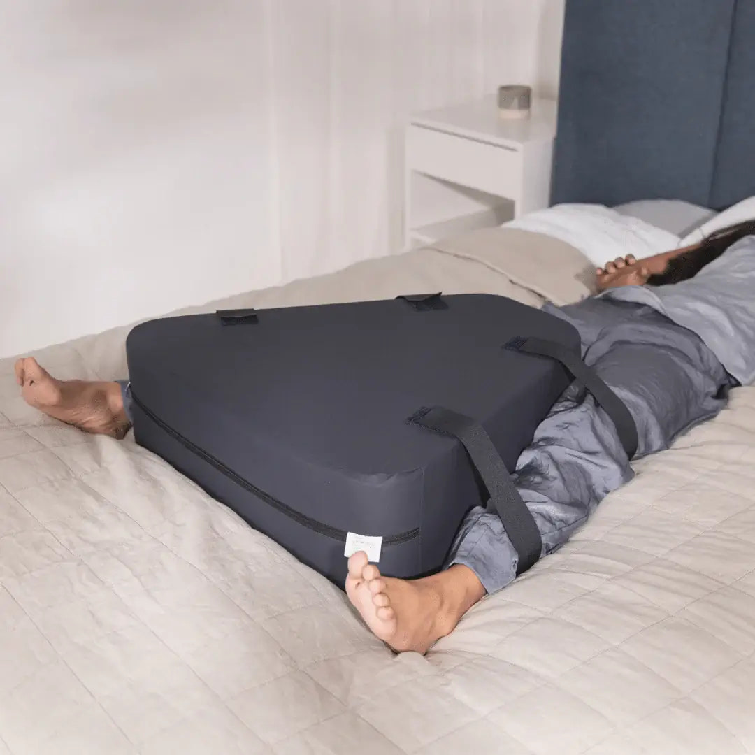 Person lying on a bed with a black compression device on their legs