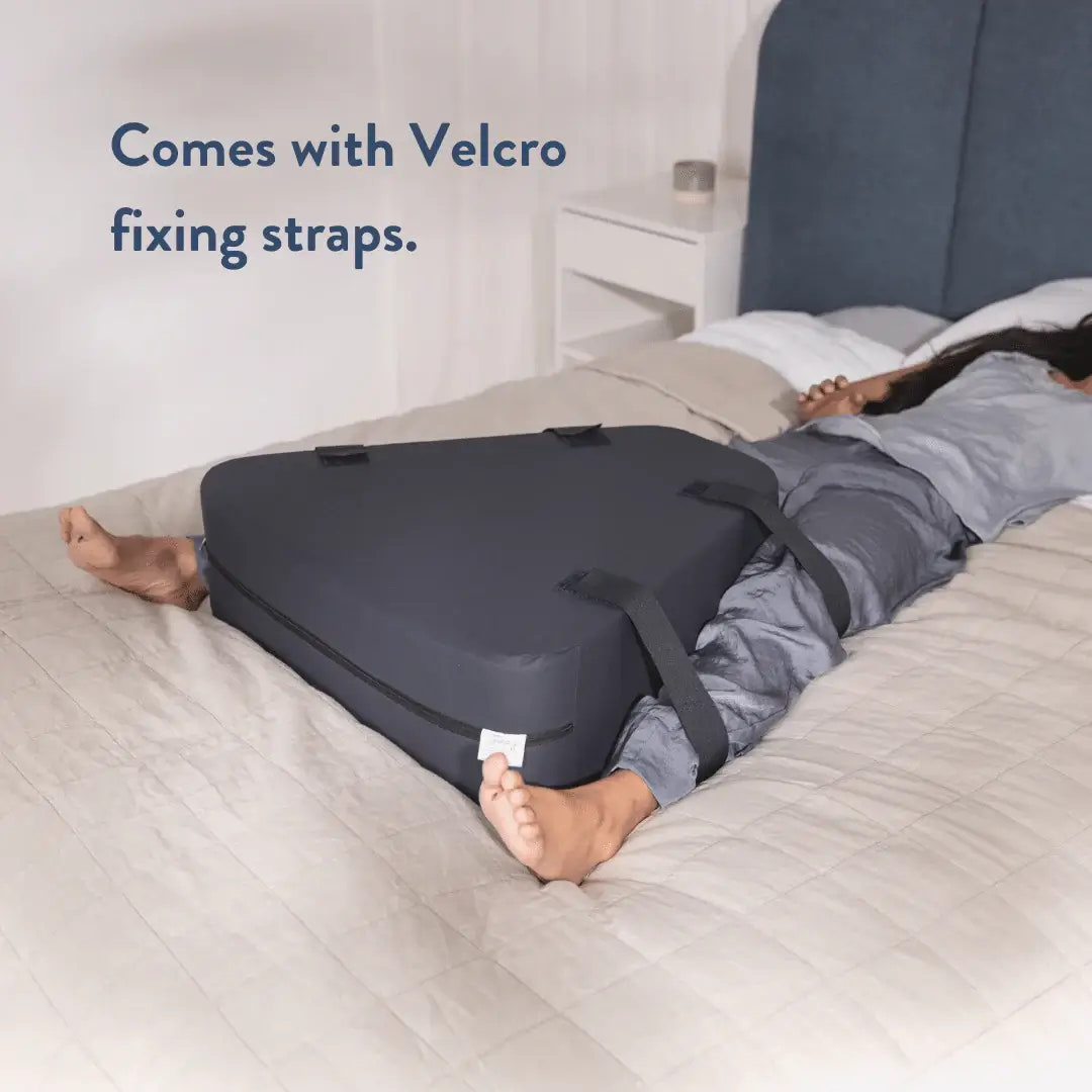 Person lying on a bed with a gray cushion and Velcro straps, text 'Comes with Velcro fixing straps.'