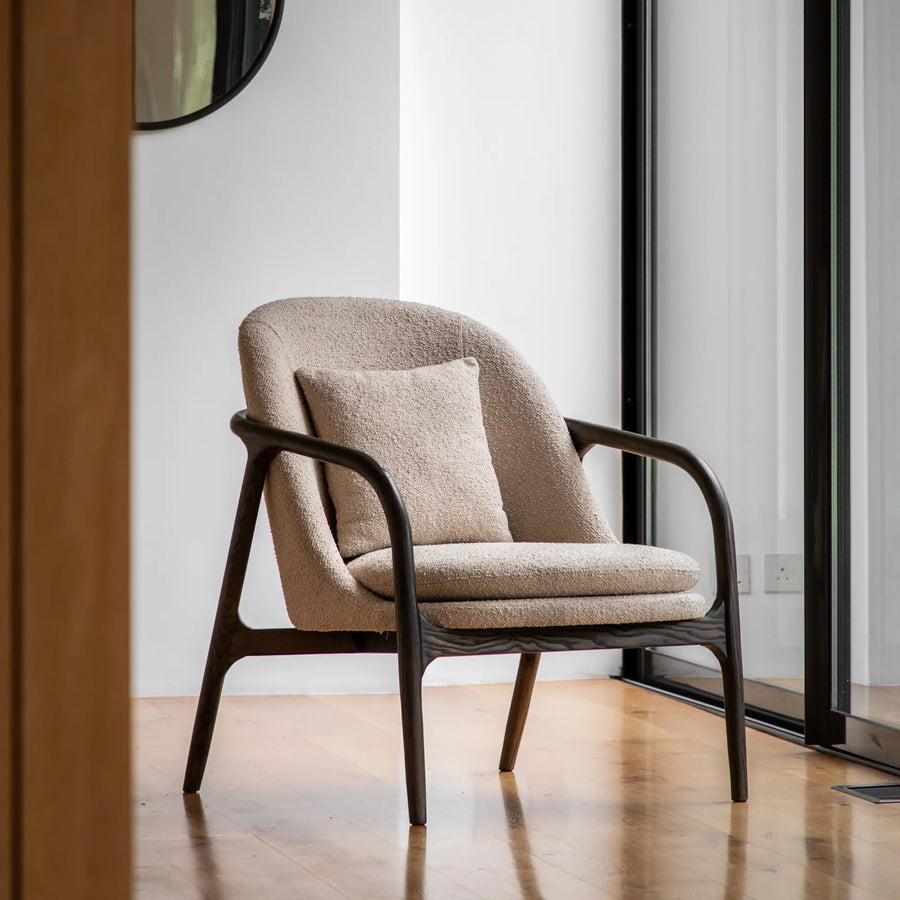 Beige upholstered armchair with dark wood frame.