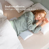 Woman sleeping on a bed with a pillow, text 'Small but effective. Won't get in your partners way & easy to store.'