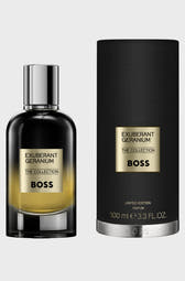 Exuberant Geranium The Collection by Hugo Boss perfume bottle next to its black cylindrical box packaging, featuring gold lettering and a silver cap, on a light gray background.