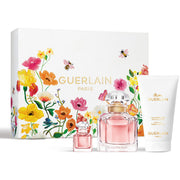 Guerlain Paris floral fragrance gift set with a large floral box, a small perfume bottle, a larger perfume bottle, and a white body care tube on a white background.