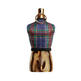 A perfume bottle shaped like a miniature mannequin torso, featuring a blue, green, and red plaid tweed upper section and a metallic gold ribbed lower section with a gold ring neck detail, set against a plain white background.