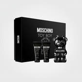 Moschino Toy Boy fragrance gift set featuring a large black box, two black body care tubes, and a glossy black bear-shaped bottle with white text, all on a white background.