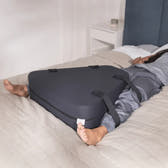 Person lying on a bed with a black compression device on their legs