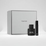 Tom Ford Ombre Leather fragrance set featuring a large textured light gray gift box, a black perfume bottle, and a slim black travel atomizer spray bottle, with a '2 pack' badge in the top right corner.